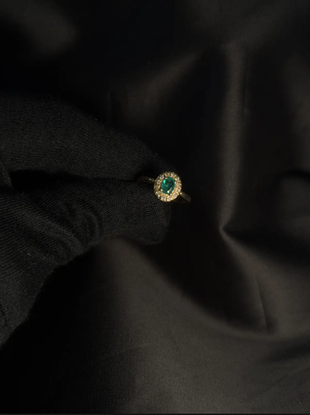 Anillo en oro amarillo 18K con esmeralda ovalada en uñas y diamantes